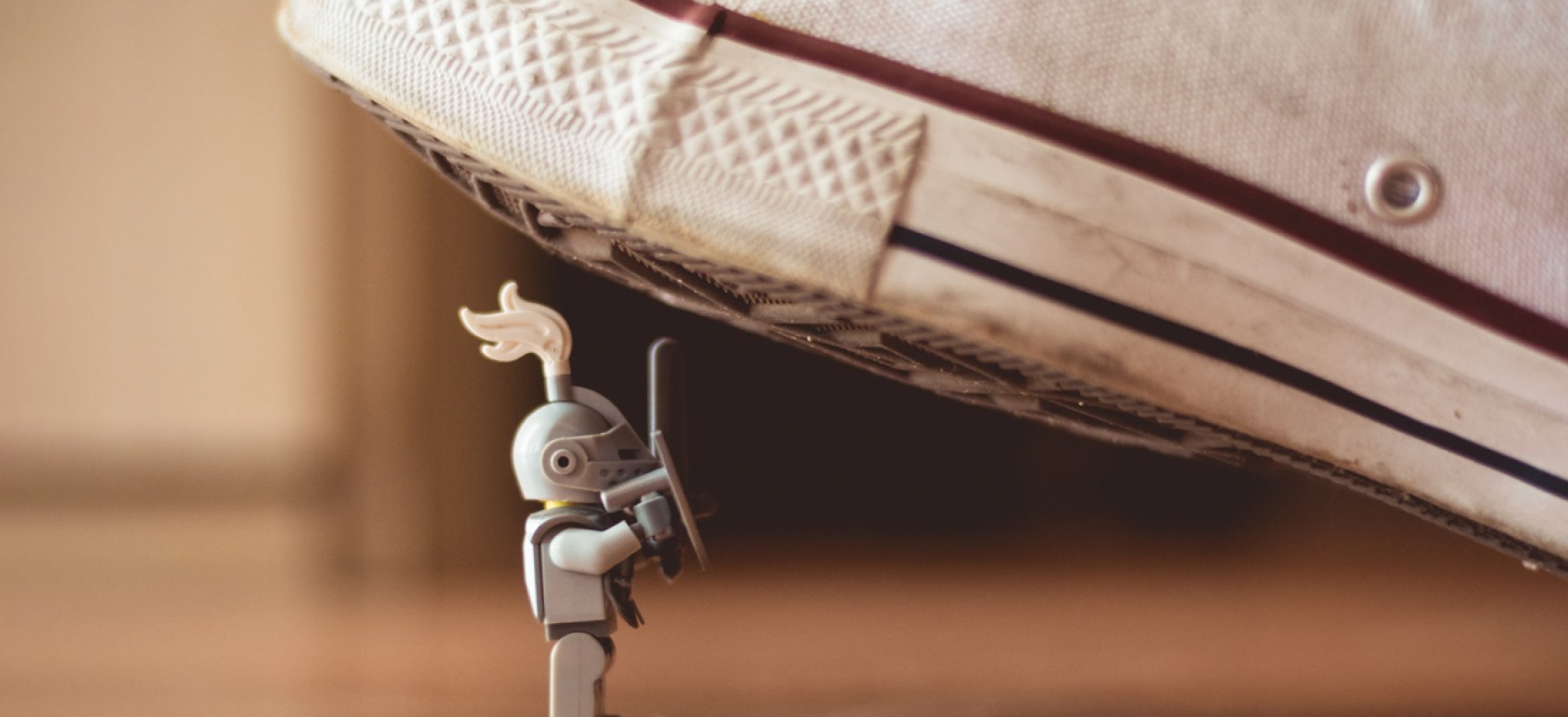 A lego knight is doing maintanence under a sports shoe