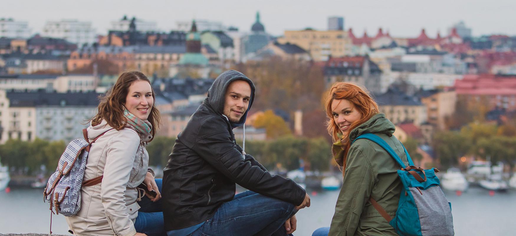 Young people hanging out on a rock with Stockholm in the background.