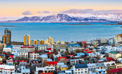 Aerial panorama of downtown Reykjavik at sunset with colorful houses and snowy mountains in the background