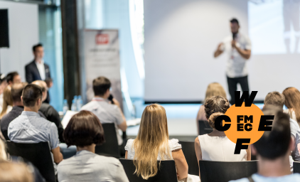 Man standing one stage pitching his idea to a seated audience.
